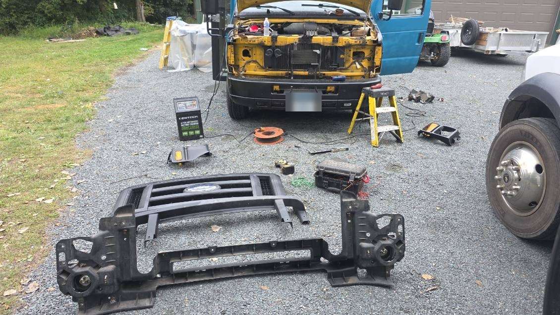 Bus front end disassembled for on-site repair, tools and parts laid out